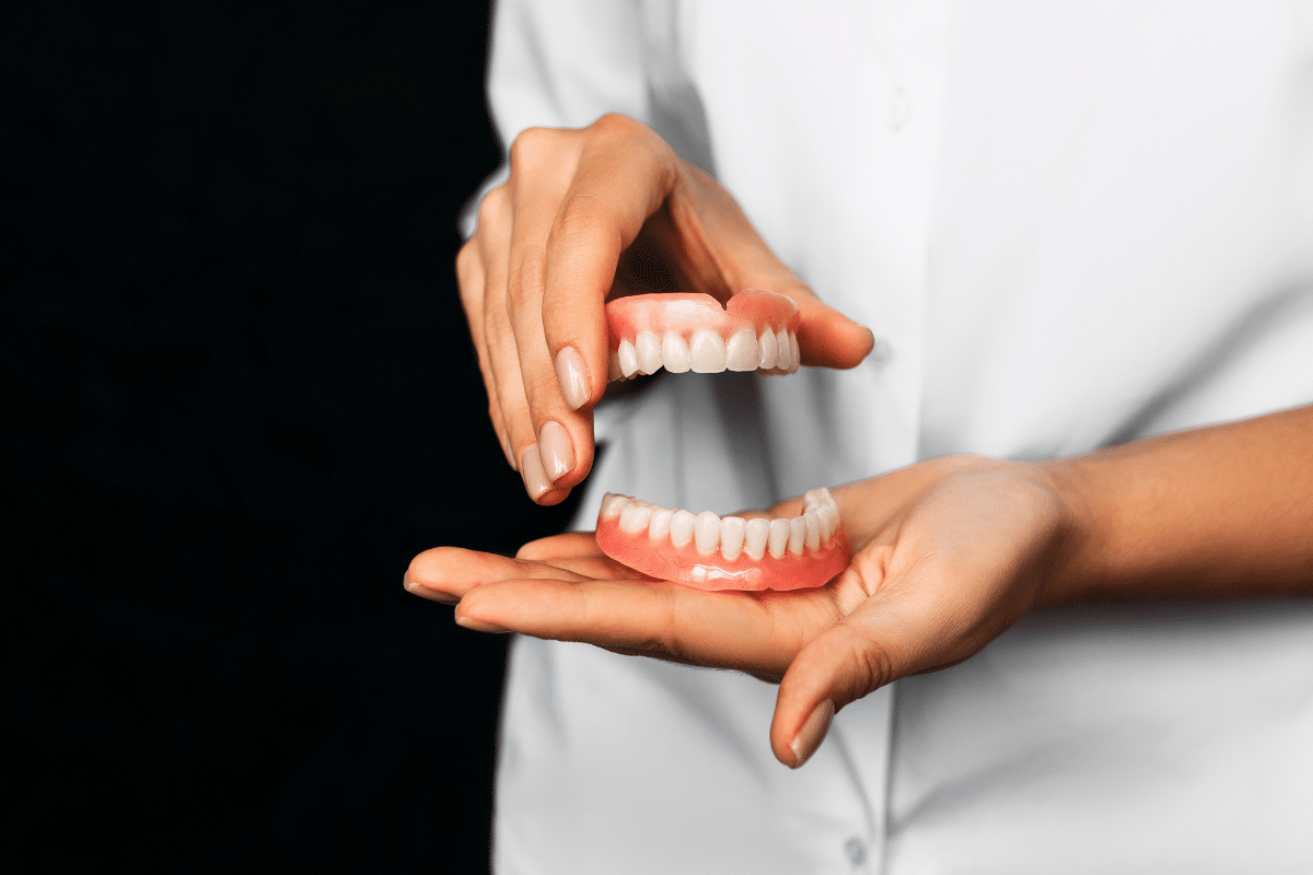 Dentist demonstrating full dentures to patient showing proper fit and oral health care.